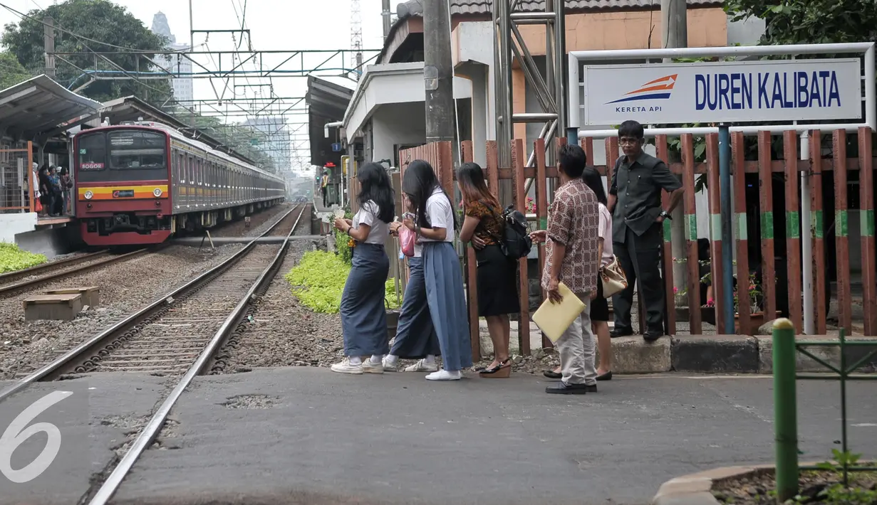 Penyeberang jalan menunggu kereta commuterline melintas di perlintasan sebidang Duren Kalibata, Jakarta, Selasa (13/9). Dirjen Kemenhub usulkan Pemprov DKI Jakarta untuk menutup 19 perlintasan sebidang di wilayah DKI Jakarta. (Liputan6.com/Yoppy Renato)