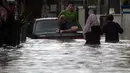 Warga duduk di atas mobil saat banjir merendam jalan dan rumah di RT 003/05, Pejaten, Jakarta, Sabtu ( 20/2/2021). Curah hujan yang tinggi sejak malam hingga dini hari mengakibatkan sejumlah kawasan terendam banjir. (merdeka.com/Imam Buhori)