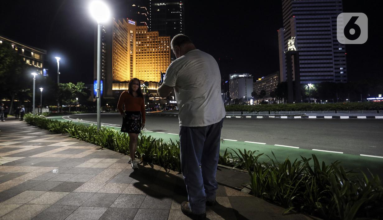 Warga berpose untuk difoto saat perayaan malam Tahun Baru di Jakarta, Jumat (31/12/2021). Polda Metro Jaya melakukan pengendalian mobilitas Crowd Free Night (malam bebas keramaian) dengan membubarkan warga yang nekat keluar rumah dan tidak mematuhi aturan. (Liputan6.com/Johan Tallo)