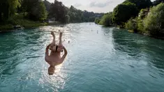 Seorang pemuda melompat ke Sungai Aare di Bern, Swiss, 21 Juni 2017. Menurut situs Britanica, Sungai Aare yang menjadi tempat tenggelamnya anak Gubernur Jawa Barat Ridwan Kamil, Emmeril Kahn Mumtadz atau Eril, memiliki panjang mencapai 295 kilometer. (Fabrice COFFRINI/AFP)