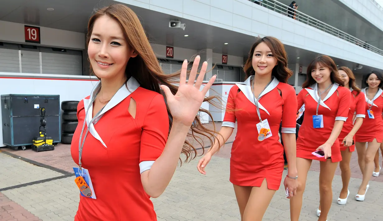 Gadis Grid atau Grid Girls berjalan sambil tersenyum di paddock jelang Grand Prix Formula 1 Korea di Yeongam, (14/10/2012). Liberty Media juga akan menerapkan penghapusan Grid Girls di ajang olahraga bermotor. (AFP FOTO / Jung Yeon-Je)