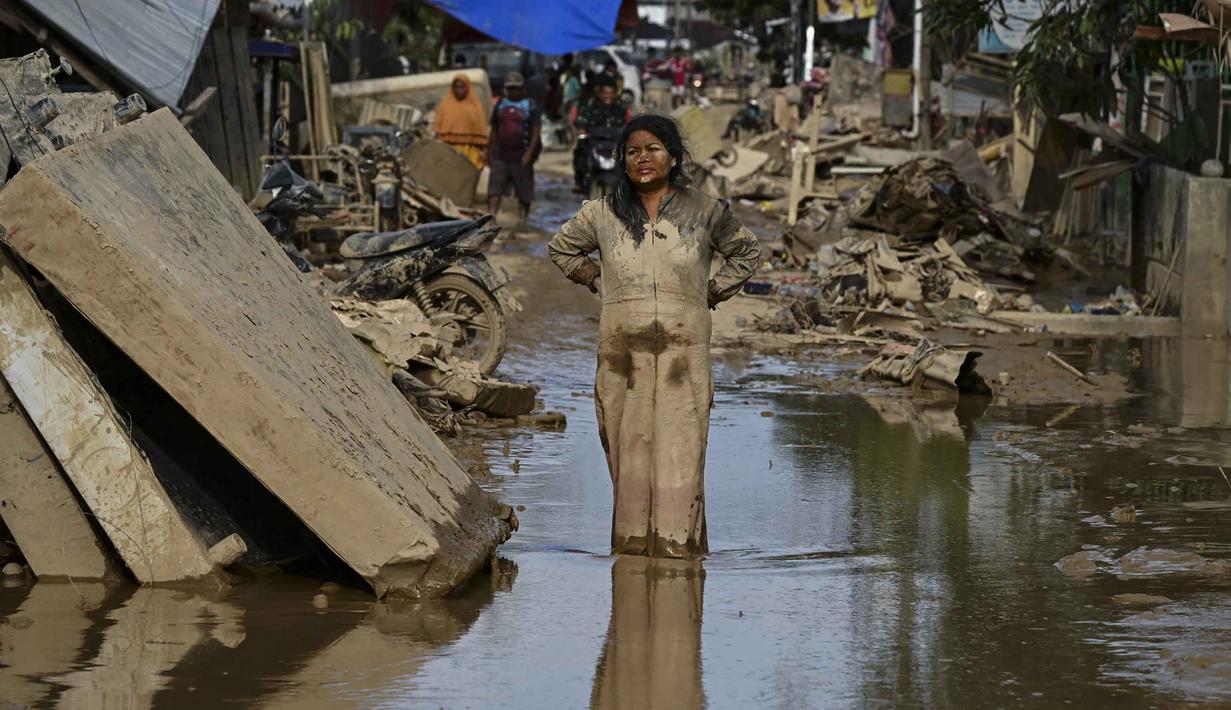Kementerian Kesehatan sudah mengeluarkan peringatan adanya potensi lonjakan dua penyakit pasca bencana banjir bandang dan tanah longsor di Aceh, yaitu Demam Berdarah Dengue (DBD) dan Leptospirosis. Tampak dalam foto, seorang perempuan berlumuran lumpur berdiri di jalanan yang dipenuhi lumpur setelah banjir bandang melanda daerah tersebut di Aceh Tamiang, Provinsi Aceh, pada Sabtu 6 Desember 2025. (YT HARIONO/AFP)