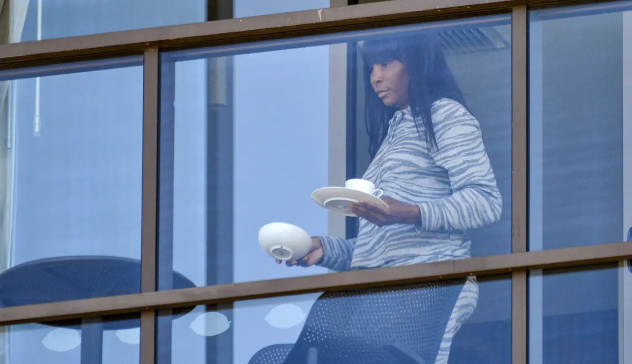 Petenis Amerika Serikat, Venus Williams, membawa minuman saat bersantai di balkon hotel di Adelaide, Australia, Jumat (22/1/2021). Venus Williams melakukan karantina selama dua minggu sebelum mengikuti ajang Australia Terbuka 2021. (AFP/Brenton Edwards)