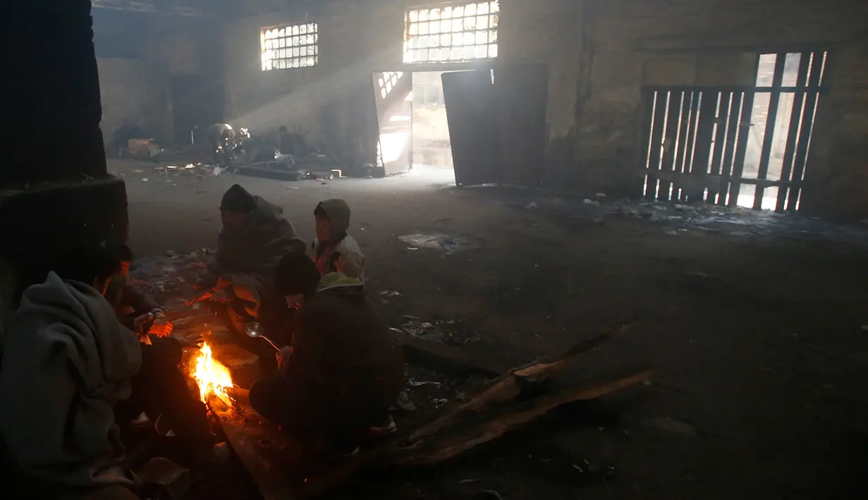 Sejumlah imigran menghangatkan tubuh mereka di sebuah gudang kosong di Belgrade, Serbia (8/1). Mereka harus bertahan hidup dibawah cuaca ekstrem dengan kebutuhan yang seadanya. (AP Photo/Darko Vojinovic)