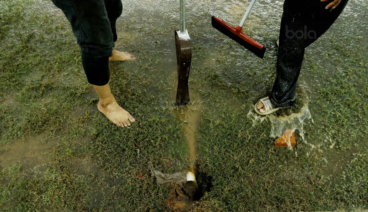 Petugas membuat lubang resapan untuk menguras air yang menggenangi lapangan di Stadion Patriot, Bekasi, Senin (13/11/2017). Drainase yang buruk menyebabkan lapangan terendam air. (Bola.com/M Iqbal Ichsan)