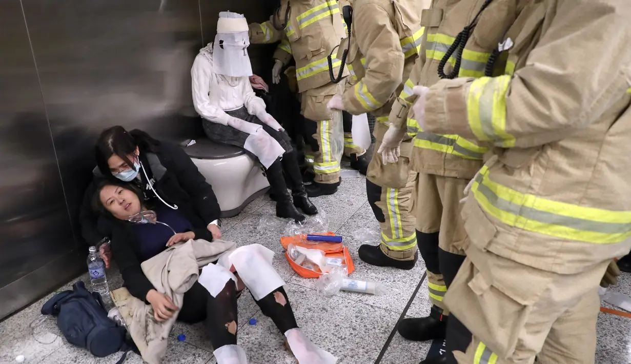 Seorang wanita korban kebakaran sedang menerima perawatan dari tim medis di Stasiun Tsim Sha Tsui, Hong Kong (10/2). Setelah polisi setempat menangkap seorang pria yang berusia 60 tahun, diduga kebakaran tersebut disengaja. (Handout / Apple Daily / AFP)