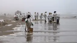 Petugas kebersihan bekerja untuk mengeluarkan minyak dari Pantai Cavero di Callao, Peru, 26 Januari 2022. Pembersihan Pantai Cavero dari tumpahan minyak kapal tanker Mare Doricum yang dihantam gelombang akibat letusan gunung berapi Tonga masih terus dilakukan. (Cris BOURONCLE/AFP)