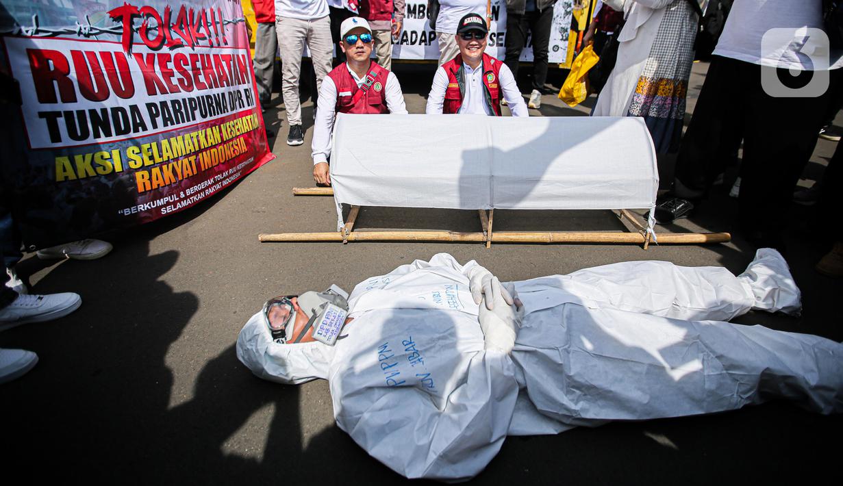 Pengunjuk rasa dari tenaga medis dan kesehatan melakukan aksi teatrikal di depan gedung MPR/DPR-DPD, Senayan, Jakarta, Selasa (11/7/2023). (Liputan6.com/Faizal Fanani)