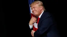 Ekspresi Donald Trump saat memeluk bendera AS pada kampanye di Tampa, Florida, AS (24/10). Pemilihan umum Presiden AS 2016 akan diadakan pada hari Selasa, 8 November 2016 dan menjadi pilpres empat tahunan ke-58. (REUTERS/Jonathan Ernst)