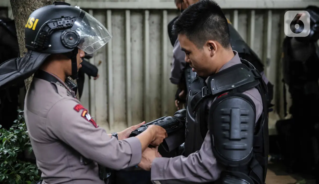 Personel Brimob bersiap mengenakan perlengkapan pelindung diri di Kawasan Bundaran HI, Jakarta, Selasa (13/10/2020). Sebanyak kurang lebih 12 ribu personel gabungan TNI, Polri dan Pemprov DKI Jakarta diterjunkan mengawal aksi tolak Undang-Undang Cipta Kerja Omnibus Law. (Liputan6.com/Faizal Fanani)
