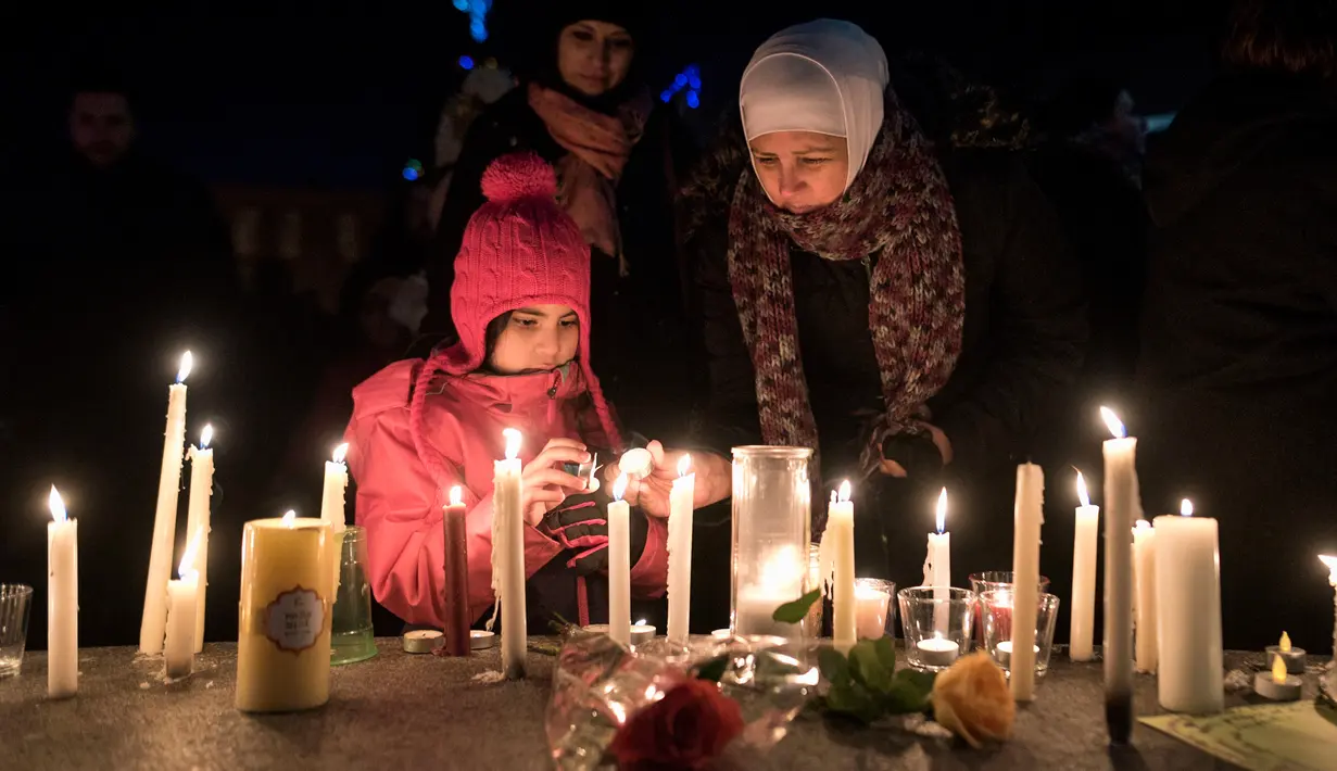 Sawsan Idris bersama putrinya menyalakan lilin dalam aksi dukungan pada komunitas muslim di Moncton, New Brunswick, Senin (30/1). Dukungan itu setelah aksi penembakan di sebuah masjid di Kota Quebec, Kanada. (Darren Calabrese/The Canadian Press via AP)