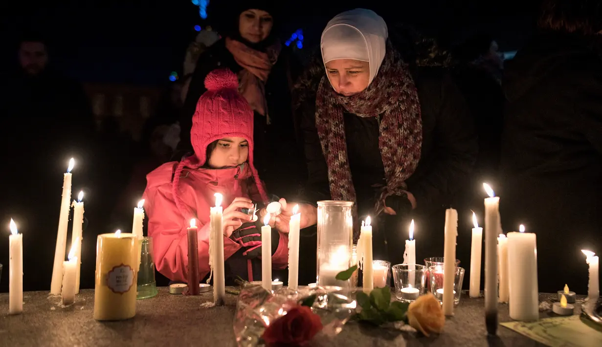 Sawsan Idris bersama putrinya menyalakan lilin dalam aksi dukungan pada komunitas muslim di Moncton, New Brunswick, Senin (30/1). Dukungan itu setelah aksi penembakan di sebuah masjid di Kota Quebec, Kanada. (Darren Calabrese/The Canadian Press via AP)