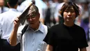 Seorang pria melindungi dirinya dari sinar matahari dengan sebuah koran saat gelombang panas di Tokyo, Jepang (1/7/2019). Cuaca panas ekstrem yang melanda Jepang telah menewaskan puluhan orang tewas dan menyebabkan ribuan orang masuk rumah sakit dengan gejala dehidrasi. (AFP Photo/Charly Triballeau)