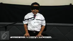 Jefri Setiawan saat bernyanyi sambil memainkan keyboard di Auditorium Kemenpora, Jakarta,  Kamis (14/11). Jefri akan memainkan 50 lagu selama 5 jam nonstop dengan mata tertutup.  (Liputan6.com/Helmi Fithriansyah)