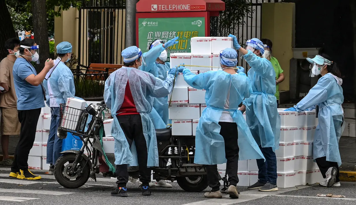 Pekerja yang mengenakan alat pelindung diri menumpuk kotak ke atas gerobak untuk dikirim saat perberlakuan lockdown karena virus corona COVID-19 di Distrik Jing'an, Shanghai, China, Rabu (18/5/2022). (Hector RETAMAL/AFP)