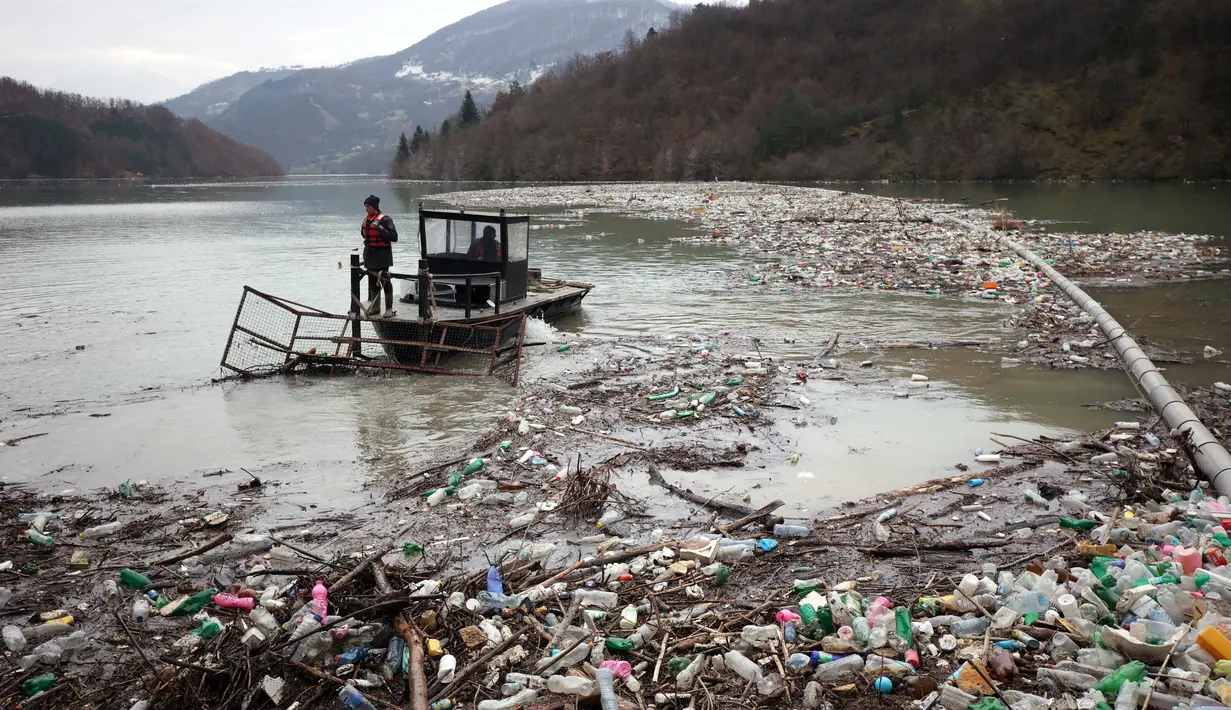 Pekerja perusahaan utilitas mendorong limbah ke tepi Sungai Lim dekat Priboj, Serbia, 30 Januari 2023. Botol plastik, papan kayu, tong berkarat, dan sampah lainnya dari tempat pembuangan sampah tepi sungai yang tidak diatur dengan baik terakumulasi selama air pasang. (AP Photo/Armin Durgut)