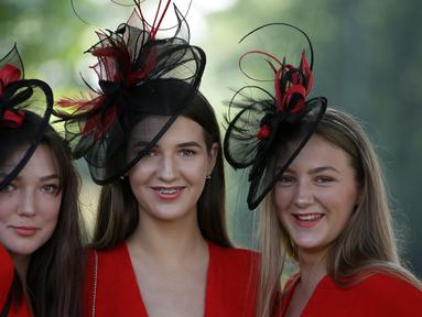 Tiga wanita memakai hiasan kepala berpose saat tiba untuk menyaksikan balap kuda Royal Ascot horse di Ascot, London, (20/6). Balap kuda ini telah diadakan di Berkshire sejak tahun 1711. (AFP Photo/Daniel Leal-Olivas)
