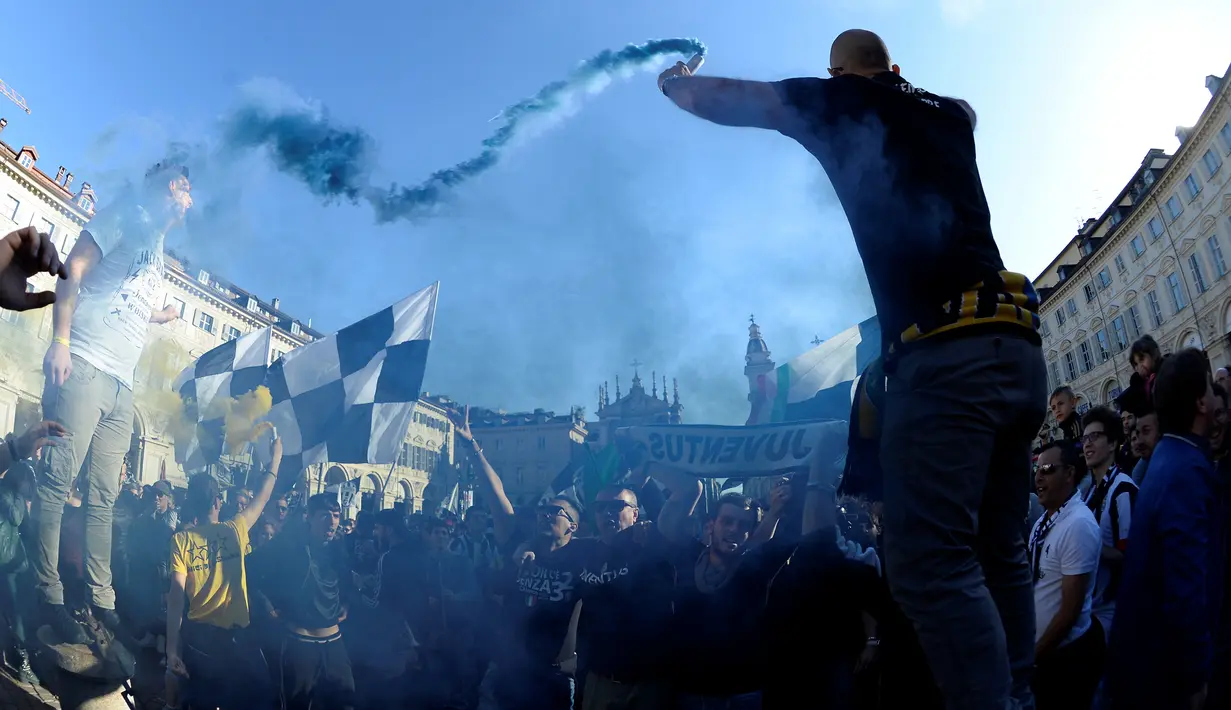 Ribuan suporter Juventus berteriak dan mengibarkan bendera merayakan kemenangan usai merebut gelar Serie A Italia di pusat kota Turin, Italia (25/4). Juventus sukses meraih lima gelar juara Serie A dalam lima musim beruntun. (REUTERS/Giorgio Perottino) 