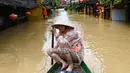 Seorang perempuan mendayung perahu di jalanan yang terendam banjir setelah hujan deras di Hoi An, Vietnam, Kamis 30 Oktober 2025. Hujan deras dengan intensitas tertinggi sepanjang sejarah memicu banjir besar di Vietnam bagian tengah. (NHAC NGUYEN/AFP)