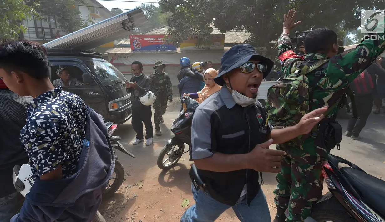Sejumlah petugas menenangan warga saat kepanikan terjadi akibat gempa susulan melanda di Tanjung pulau Lombok, NTB, Kamis (9/8).(AFP/ ADEK BERRY)