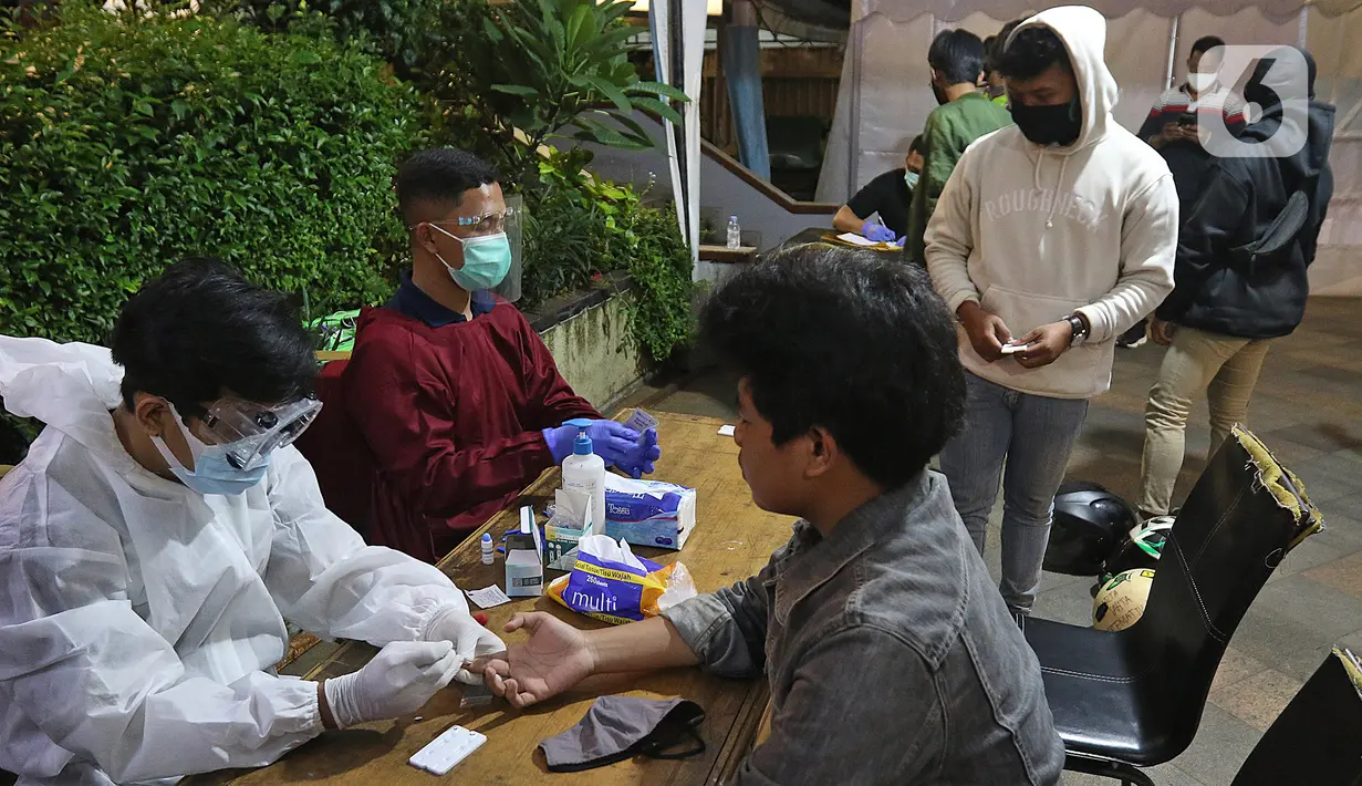Petugas melakukan rapid test terhadap pelanggar protokol kesehatan COVID-19 pada patroli penegakkan di Jalan Veteran, Jakarta Pusat, Sabtu (26/12/2020). Operasi gabungan itu dilakukan menyusul meningkatnya penyebaran COVID-19 di Ibu kota. (Liputan6.com/Herman Zakharia)