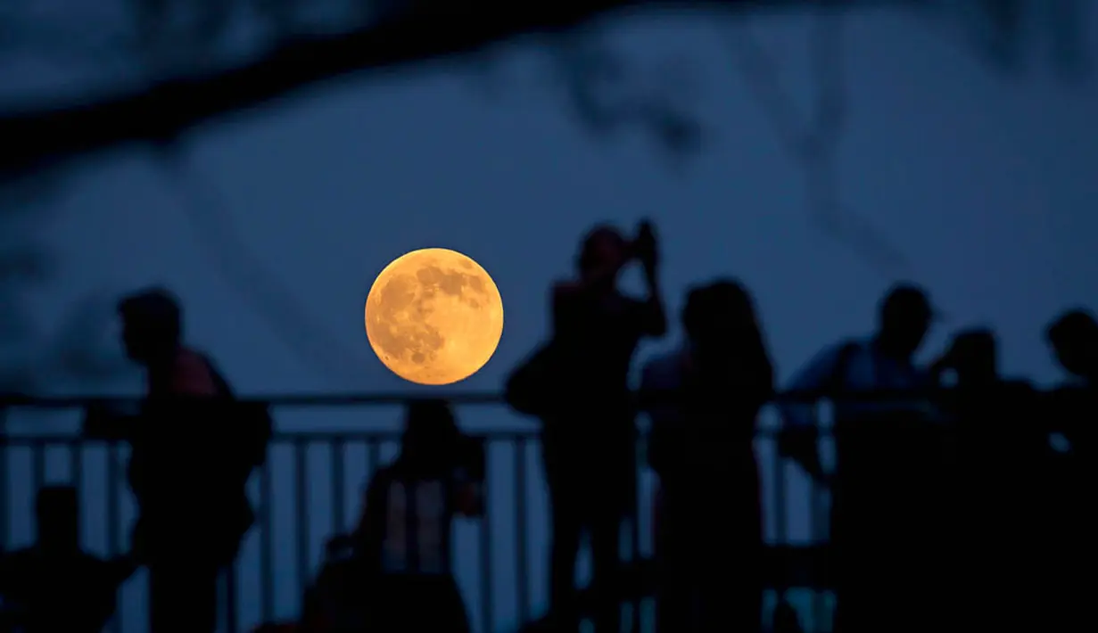  Orang-orang berdiri di sebuah jembatan di Manhattan, New York untuk melihat bulan purnama (REUTERS / Carlo Allegri)