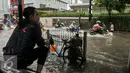 Seorang warga menonton sejumlah kendaraan yang nekat menerobos bajir di Jalan Kemang Raya, Jakarta, Jumat (11/11). Diguyur hujan deras, Jalan Kemang Raya kembali tegenang air. (Liputan6.com/Yoppy Renato)
