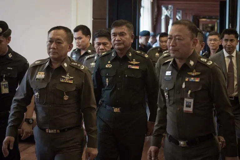 Jenderal Manas Kongpan (tengah) dikawal dua polisi saat ia menyerahkan diri pada Juni 2015 (NICOLAS ASFOURI / AFP)