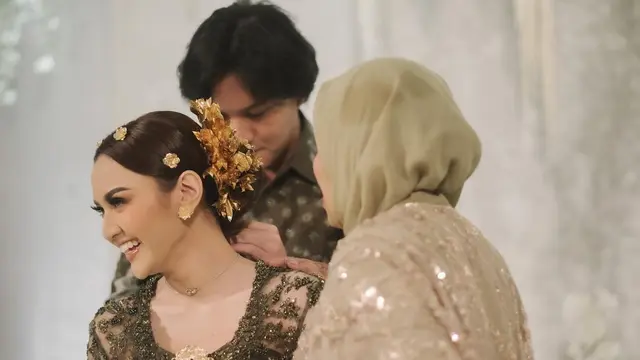Rizky Febian tampak memasangkan sebuah kalung di leher tunangannya, Mahalini Raharja.