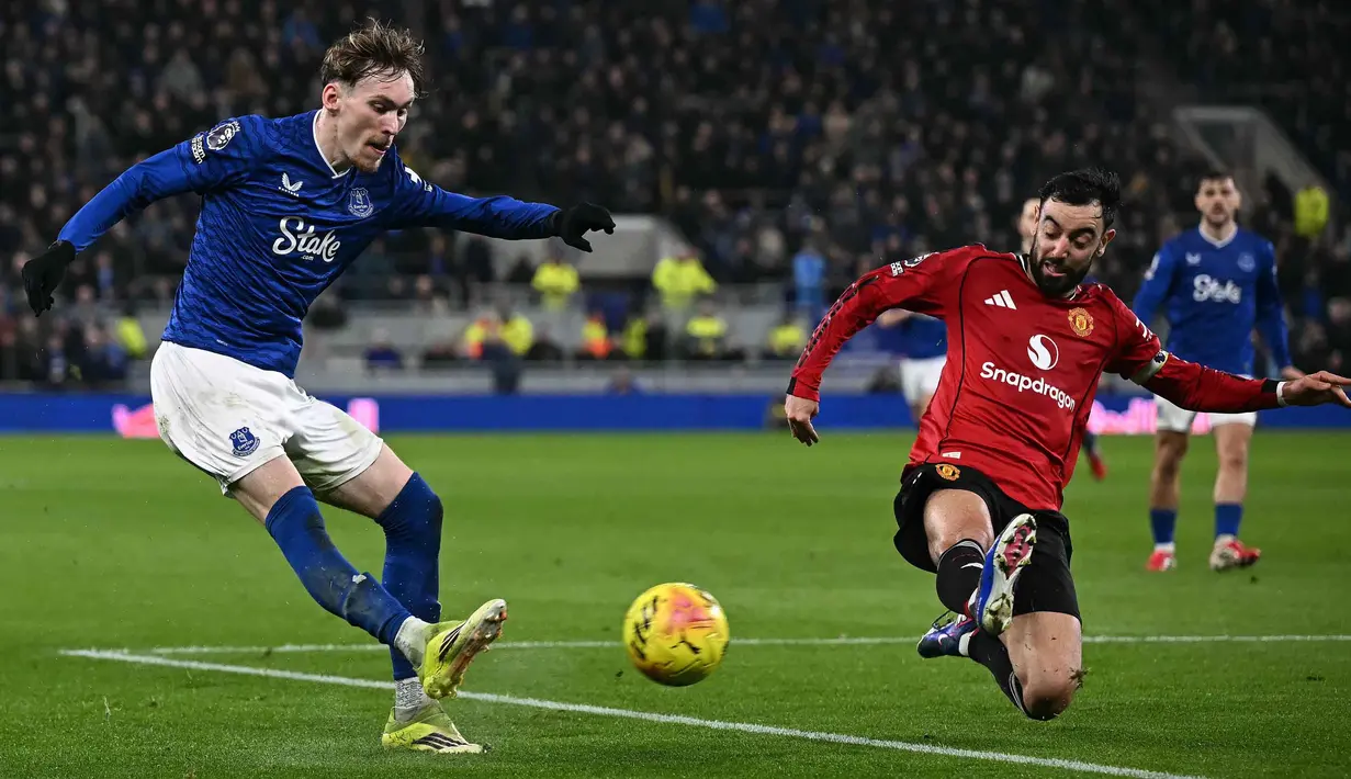 Manchester United sempat dibuat frustrasi oleh Everton yang menerapkan skema bertahan rapat di 15 menit pertama. Tampak dalam foto, gelandang Everton asal Inggris, James Garner (kiri), melepaskan tembakan melewati gelandang Manchester United asal Portugal, Bruno Fernandes, selama pertandingan pekan ke-27 Liga Primer Inggris 2025/2026 di Stadion Hill Dickinson, Liverpool, barat laut Inggris, Senin 23 Februari 2026 waktu setempat atau Selasa 24 Februari 2026 dini hari WIB. (Paul ELLIS/AFP)