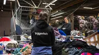 Pekerja di Artikel2, Stockholm, Swedia, bekerja tanpa henti menyortir pakaian bekas yang menjadi limbah tekstil. (dok. Jonathan NACKSTRAND / AFP)
