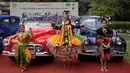 Penari berpose dengan mobil vintage yang baru direstorasi dalam pameran 21 Gun Salute Heritage and Cultural Trust di New Delhi, India, Selasa (6/2). Lebih dari 100 mobil vintage dan klasik akan berpartisipasi di reli tahunan. (AP Photo/Altaf Qadri)