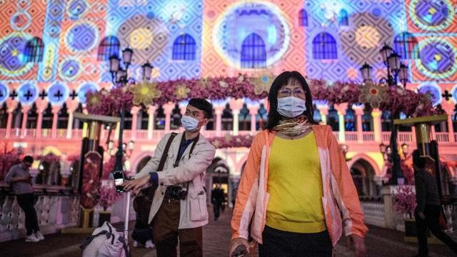 Pengunjung mengenakan masker saat mereka berjalan di luar resor hotel kasino Venesia di Macau, yang pada 22 Januari melaporkan kasus pertama dari Virus Corona Baru.