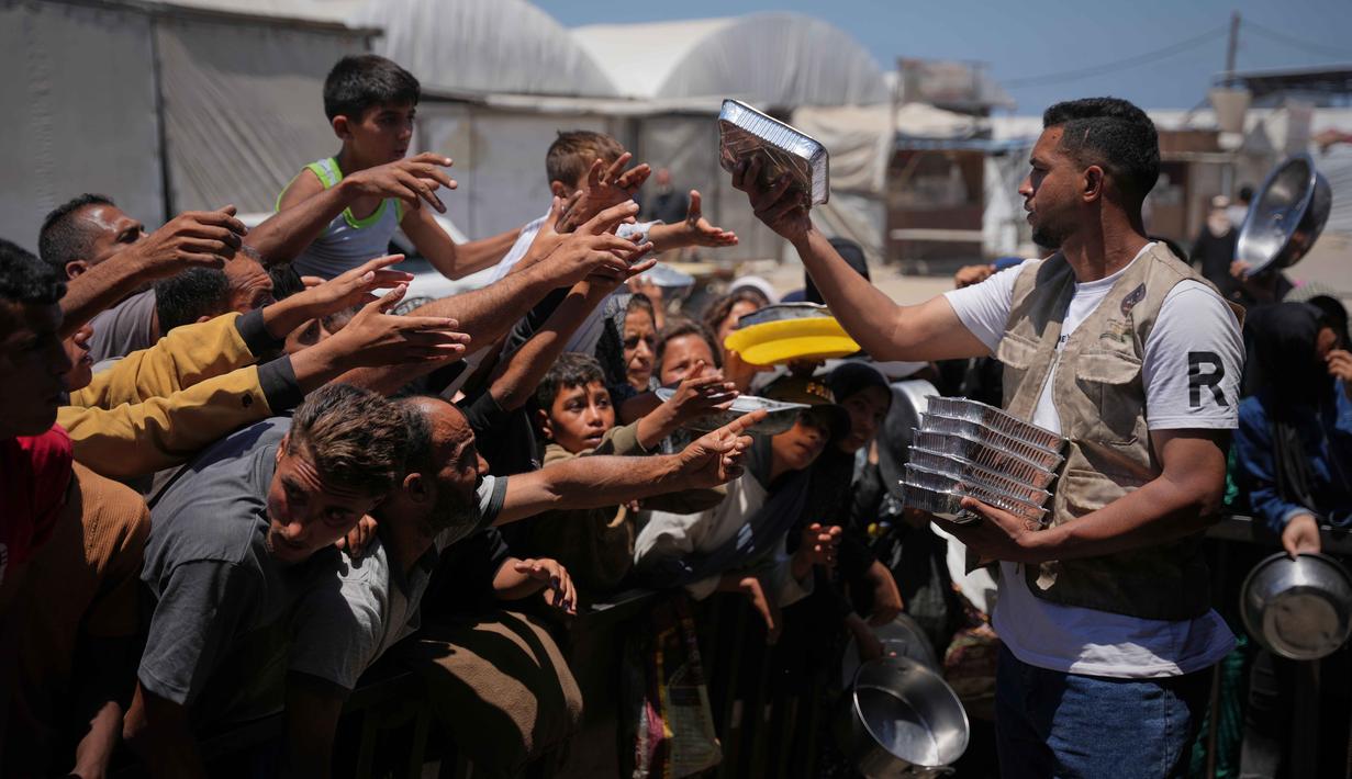 Warga Palestina menerima sumbangan makanan di pusat distribusi di Khan Younis, Jalur Gaza, Rabu 27 Mei 2026. (AP Photo/Abdel Kareem Hana)