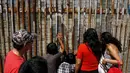 Warga berbincang dengan keluarga mereka di pagar perbatasan antara Meksiko dan Amerika Serikat, Playas Tijuana, Meksiko, (12/4).Hal ini dilakukan karena banyak warga yang tak punya biaya atau visa untuk mengunjungi keluarganya. (REUTERS / Jorge Duenes)