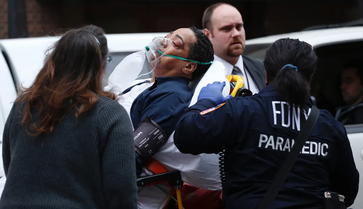 Seorang pria dievakuasi menuju ambulans akibat kereta komuter Long Island Road keluar jalur di Brooklyn Atlantic Terminal, New York, Rabu (4/1). Rangkaian kereta anjlok di jalur 6 setelah menabrak penghalang saat memasuki stasiun (AFP PHOTO/Kena Betancur)