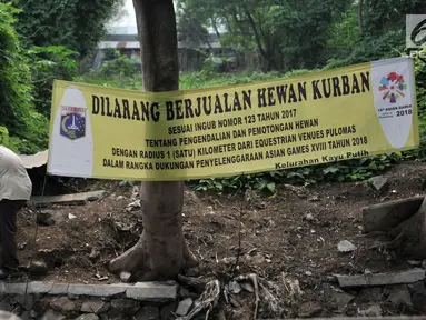 Pekerja beraktivitas dekat spanduk larangan di kawasan Pulomas, Jakarta, Rabu (4/7). Pemprov DKI melalui Sudin Ketahanan Pangan, Kelautan dan Pertanian (KPKP) memasang spanduk larangan berjualan hewan kurban jelang Idul Adha (Merdeka.com/Iqbal S. Nugroho)