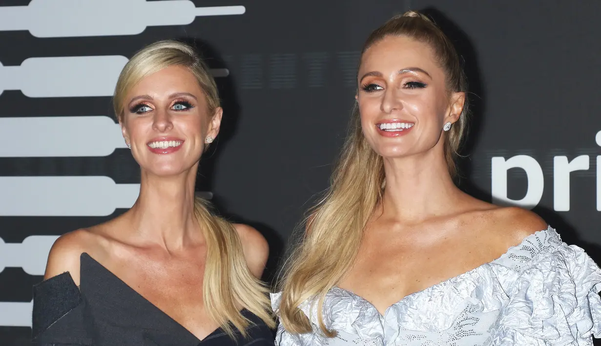 Paris Hilton bersama adiknya Nicky Hilton Rothschild tersenyum saat berpose menghadiri Savage x Fenty selama New York Fashion Week di Barclays Center di New York City (10/9/2019). Paris Hilton tampil anggun memamerkan tubuh langsingnya dalam balutan gaun mini biru. (AFP Photo/Jim Spellman)