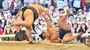 Pegulat sumo membanting lawannya saat bertanding dalam turnamen Honozumo di Kuil Yasukuni, Tokyo, Jepang, 15 April 2019. Turnamen ini digelar setiap tahun. (TRIBALLEAU CHARLY/AFP)