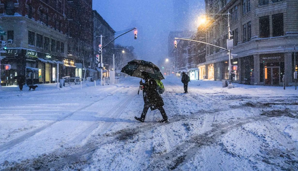 Para komuter berjalan melewati salju selama larangan perjalanan di seluruh kota New York pada Senin 23 Februari 2026. Badai musim dingin yang kuat melanda kawasan Atlantik Tengah dan Timur Laut Amerika Serikat (AS), membawa hujan salju lebat di Kota New York. (Ryan Murphy/Getty Images North America/Getty Images via AFP)