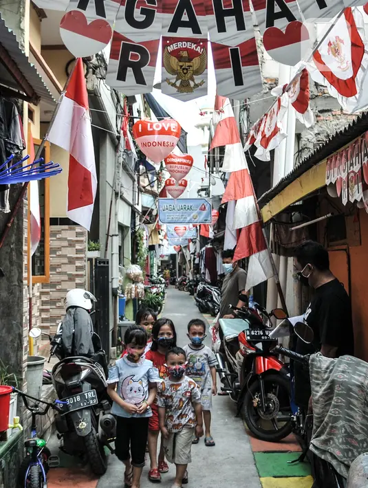 Anak-anak melintas di Gang A, RT 10/11, Pademangan Timur, Jakarta, Rabu (5/8/2020). Ide menghias gang tersebut dicetus oleh Ketua RT setempat, Farli (48), dan disambut antusias oleh warga yang turut membantu pemasangan atribut HUT ke-75 RI secara swadaya. (merdeka.com/Iqbal S. Nugroho)