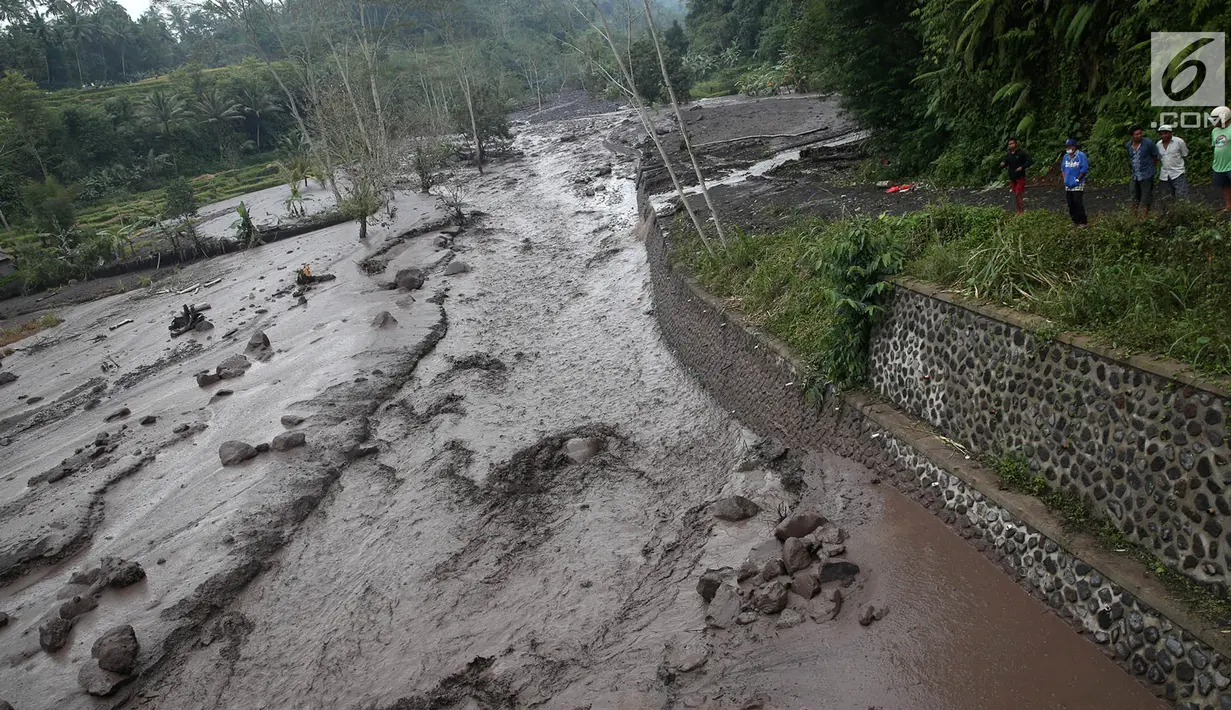 Warga mengamati aliran lahar dingin yang melintasi Sungai Yeh Sah di Karangasem, Bali, Sabtu (2/12). Banjir lahar dingin ini juga mengundang pengendara yang melintas untuk berfoto dan melihat-lihat. (Liputan6.com/Immanuel Antonius)