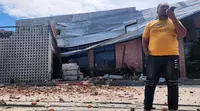 Seorang pria berbicara di telepon selulernya di dekat sebuah bangunan yang rusak akibat gempa di Palu, Sulawesi Tengah, Selasa 16 Juni 2026. (AP Photo/Josua Marunduh)