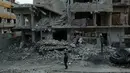 Warga mengamati bangunan yang mengalami kerusakan di Ghouta Timur, Minggu (25/2). Data PBB menyebut ada sekitar 400.000 orang yang masih terjebak dalam perang antara pasukan rezim Suriah dengan pasukan pemberontak di Ghouta Timur. (HAMZA AL-AJWEH/AFP)