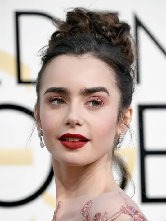 Aktris Lily Collins bereaksi saat berpose di karpet merah Golden Globe Awards di California, Minggu (8/1). Penampilan Lily semakin sempurna dengan lipstik merah yang dipadukan make-up sederhana. (Frazer Harrison/GETTY IMAGES NORTH AMERICA/AFP)