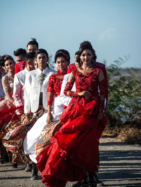 Model dengan balutan busana tradisional berlenggak-lenggok saat fashion show di tanggul Lapindo Porong, Sidoarjo, Jawa Timur, Selasa (13/8/2019). Sebanyak 15 model menunjukkan mode busana yang didominasi warna merah dan putihdalam acara tersebut. (Photo by JUNI KRISWANTO / AFP)