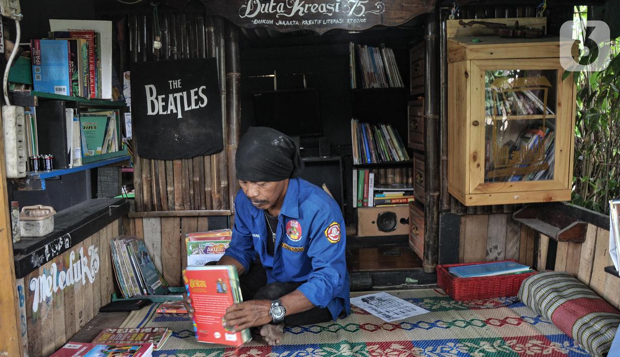 Iwan saat merapikan buku yang telah dibaca oleh anak-anak di perpustakaan Bale Buku Meleduk (Membaca Literasi Dukuh) 75 di Jalan Dukuh V, Kelurahan Dukuh, Kecamatan Kramat Jati, Jakarta Timur, Rabu (24/8/2022). Meski tidak terlalu besar, perpustakaan ini memiliki keunikan karena dibangun oleh Iwan dengan memanfaatkan barang-barang bekas yang didapat dari sekitar saat rutinitas sebagai PPSU. (merdeka.com/Iqbal S. Nugroho)