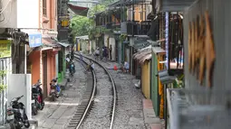 Warga duduk di atas rel kereta yang populer sebagai lokasi selfie di Hanoi, Vietnam, Kamis (10/10/2019). Banyaknya wisatawan nongkrong sampai selfie di lintasan kereta membuat pihak berwenang menutup jajaran kafe yang berdiri di samping rel tersebut. (Nhac NGUYEN/AFP)