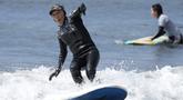 Seiichi Sano, pria Jepang berusia 89 tahun, meniti ombak saat bermain "surfing" (selancar) di Pantai Katase Nishihama, di Fujisawa, selatan Tokyo, Kamis (30/3/2023). (AP Photo/Eugene Hoshiko)
