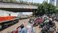 Pengendara menanti di pintu perlintasan kereta sebidang di Jalan KH Mas Mansyur, Jakarta, Senin (30/10). Perlintasan sebidang ini rencananya segera ditutup karena dianggap menjadi salah satu titik kemacetan di Jakarta Pusat. (Liputan6.com/Angga Yuniar)